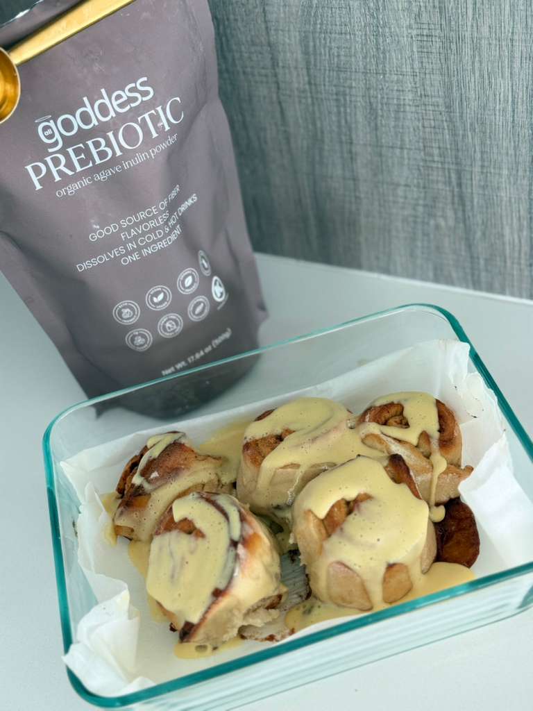 Healthy high-protein high-fiber cinnamon rolls drizzled with vanilla protein glaze, served alongside a bag of Goddess Prebiotic