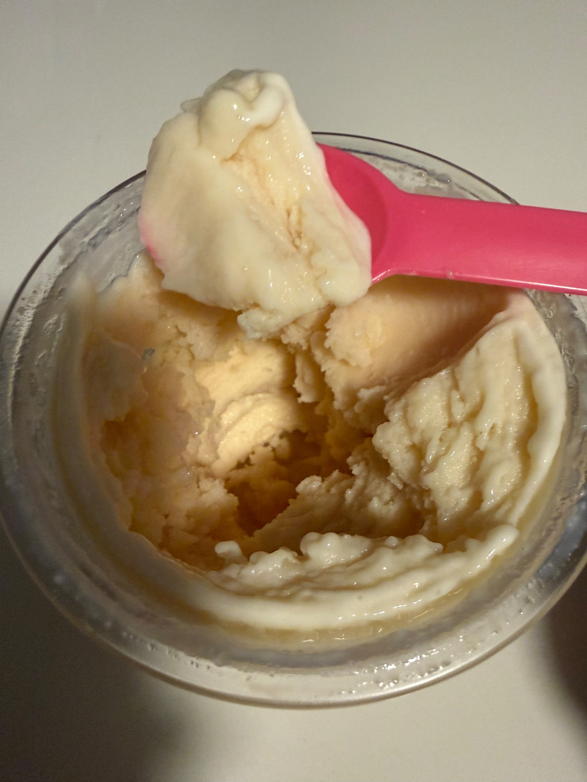 A pint of creamy vanilla protein ice cream made in the Ninja Creami, with a pink spoon resting on top