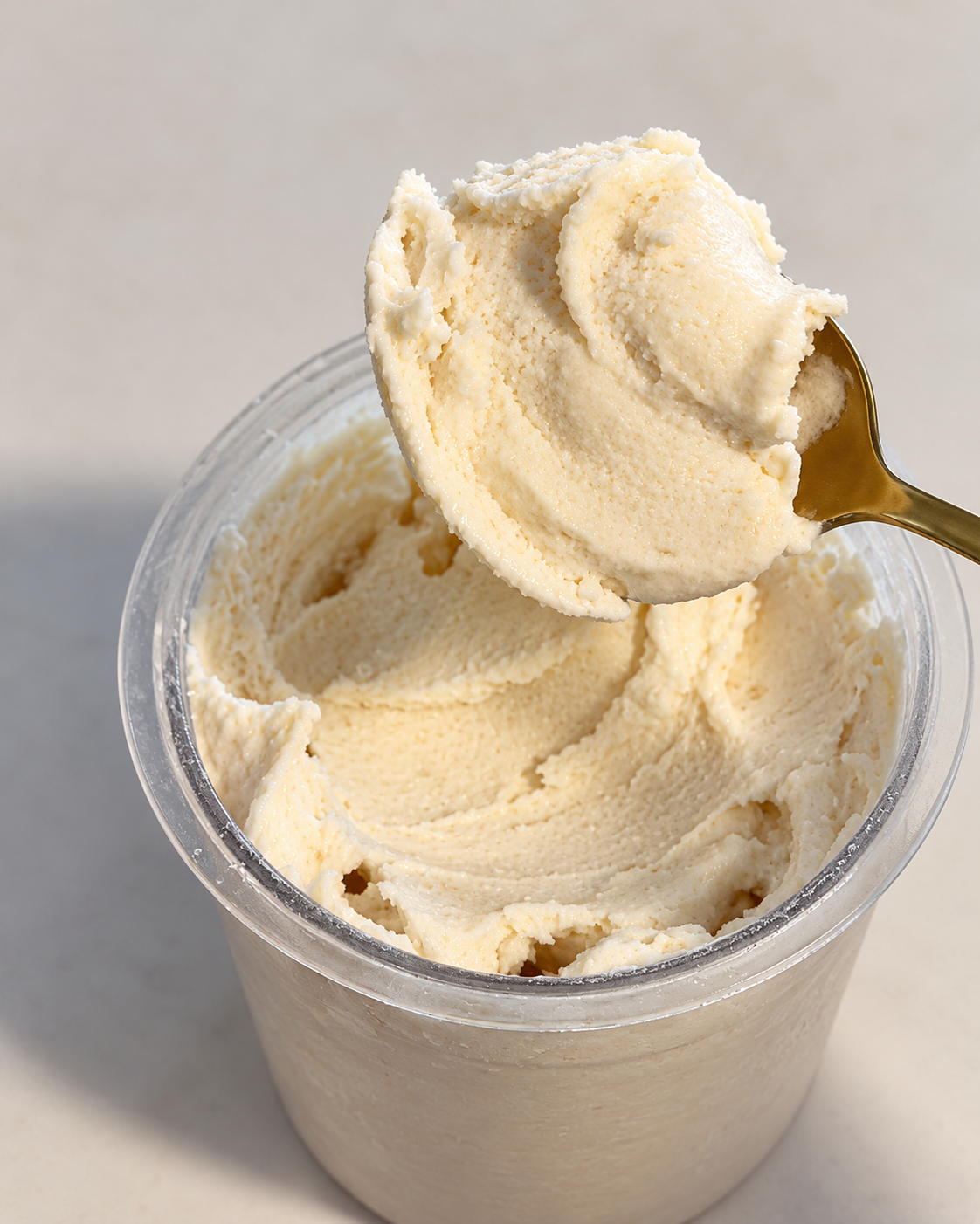 Creamy cake batter protein ice cream on a spoon above a Ninja Creami pint